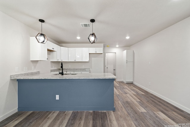 kitchen featuring hardwood / wood-style floors, sink, hanging light fixtures, white cabinetry, and kitchen peninsula