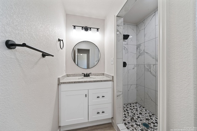 bathroom featuring hardwood / wood-style flooring, vanity, and a tile shower