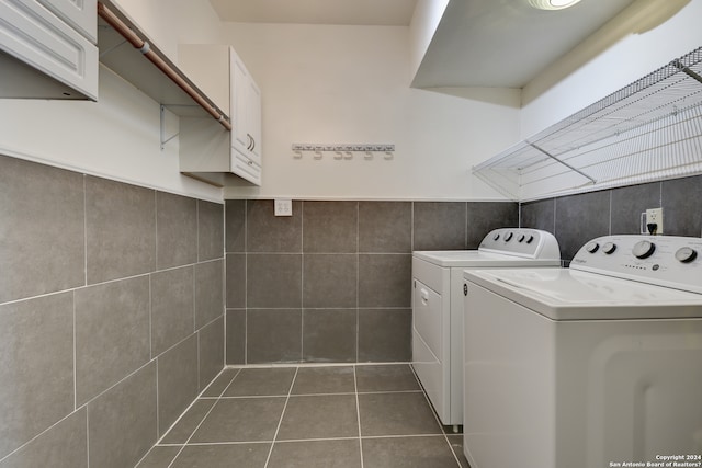 laundry area featuring tile walls, dark tile flooring, and separate washer and dryer