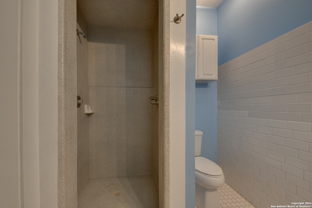 bathroom with toilet, tile floors, and a tile shower