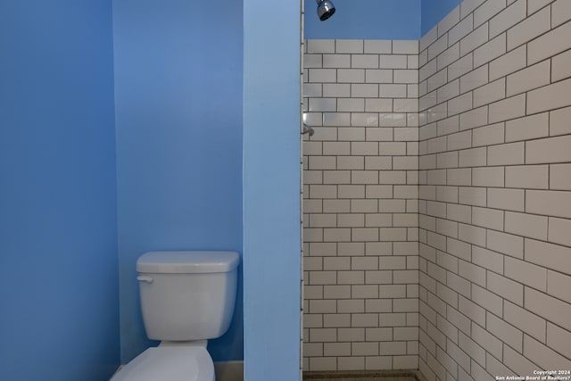 bathroom with tiled shower and toilet