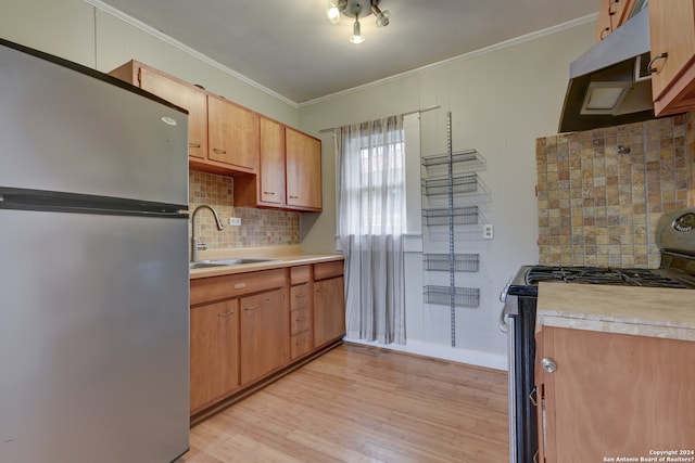 kitchen featuring sink, backsplash, stove, stainless steel fridge, and light hardwood / wood-style flooring