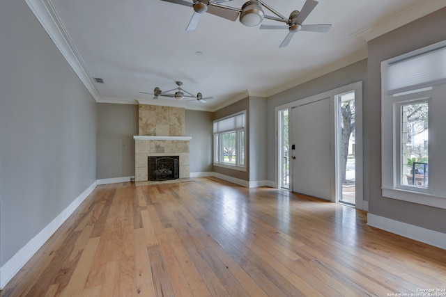 unfurnished living room with ceiling fan, a tile fireplace, light wood-type flooring, and crown molding