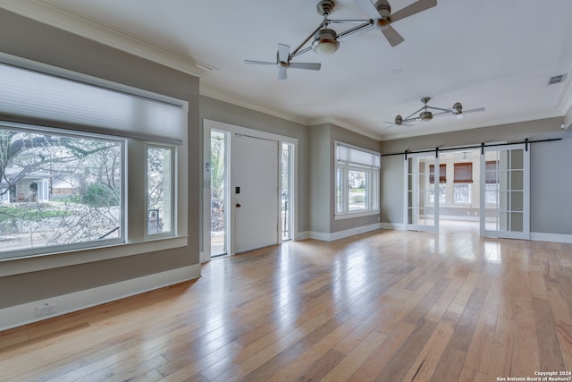 foyer featuring light hardwood / wood-style floors, crown molding, ceiling fan, and a barn door