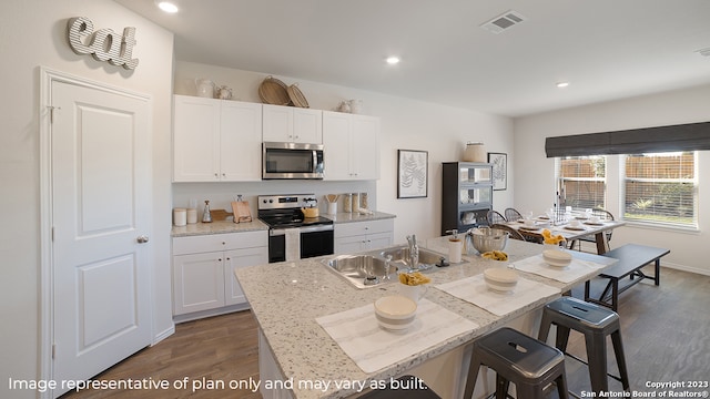 kitchen featuring a kitchen island with sink, dark wood-type flooring, sink, appliances with stainless steel finishes, and white cabinetry