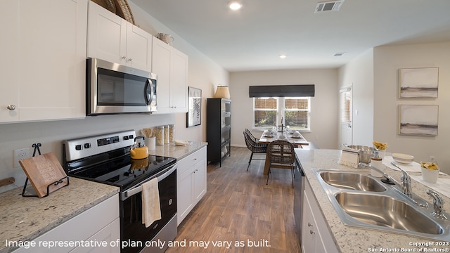 kitchen with white cabinets, sink, light stone countertops, appliances with stainless steel finishes, and dark hardwood / wood-style flooring