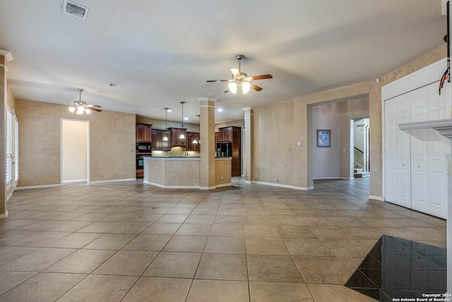 unfurnished living room with decorative columns, ceiling fan, and light tile floors