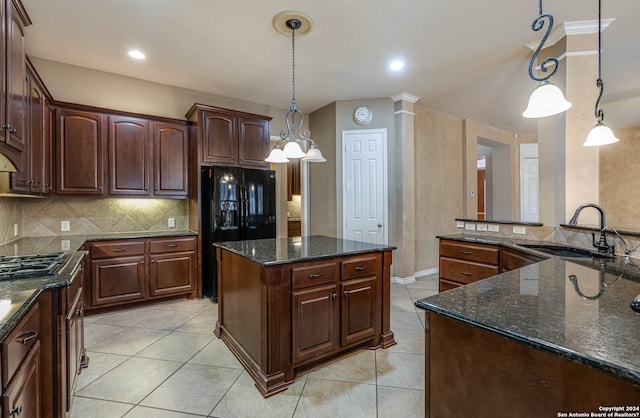 kitchen featuring hanging light fixtures, backsplash, light tile flooring, dark stone counters, and ornate columns