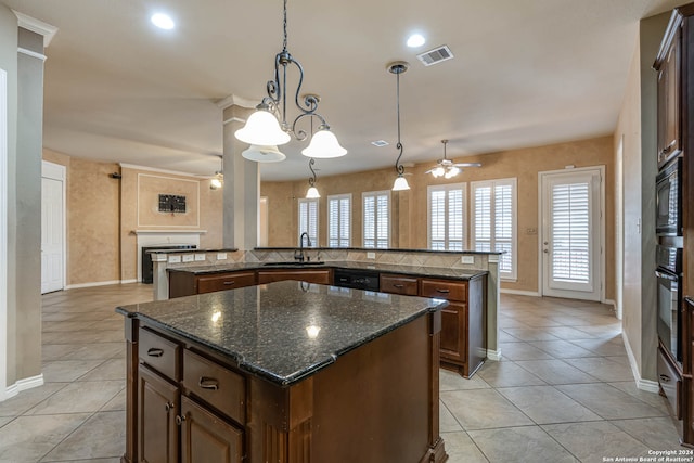 kitchen featuring ceiling fan with notable chandelier, a center island, black appliances, and pendant lighting