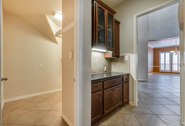 kitchen with decorative light fixtures, backsplash, light tile floors, a chandelier, and dark brown cabinets