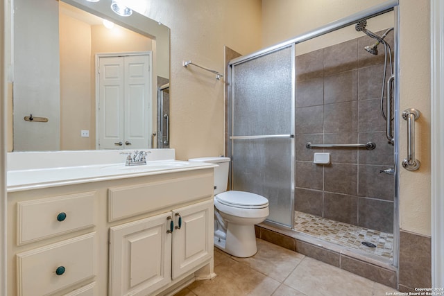 bathroom with toilet, a shower with door, large vanity, and tile flooring