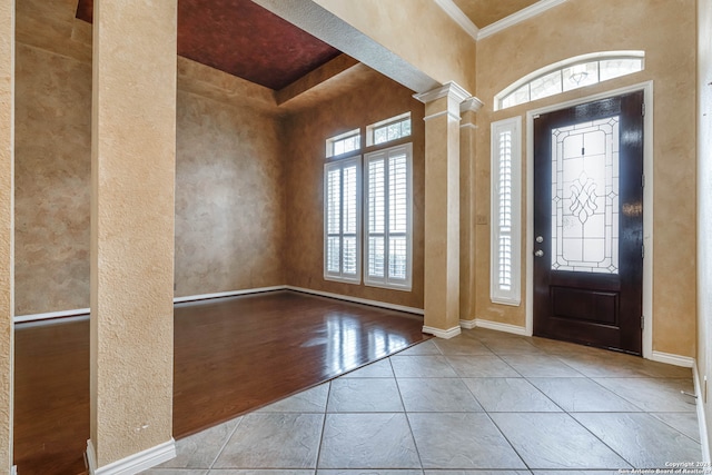 foyer with ornamental molding, light tile floors, and ornate columns