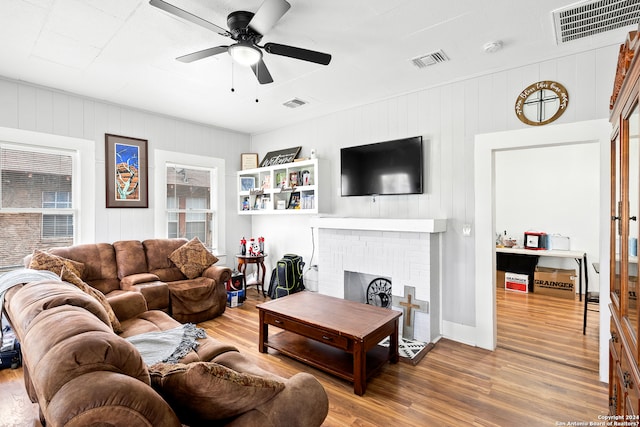 living room featuring light hardwood / wood-style flooring, ceiling fan, and a fireplace