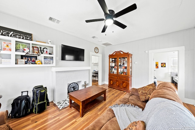 living room with a fireplace, ceiling fan, and light hardwood / wood-style flooring