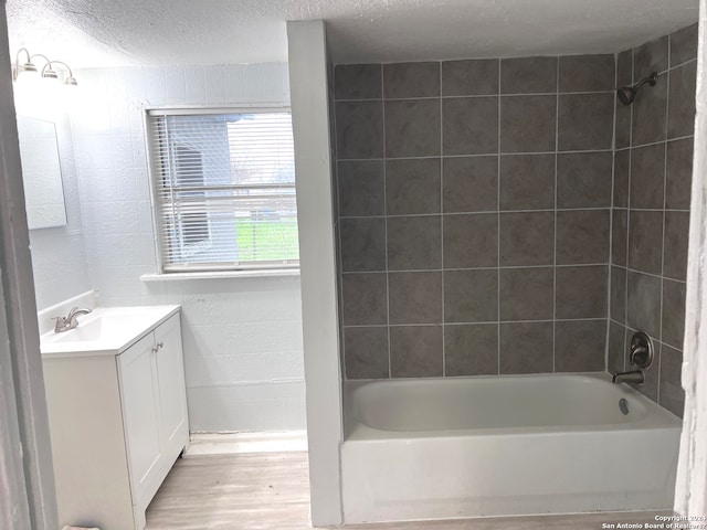 bathroom with tiled shower / bath, a textured ceiling, hardwood / wood-style floors, and vanity