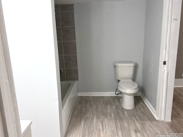 bathroom featuring hardwood / wood-style floors, toilet, and tiled shower / bath