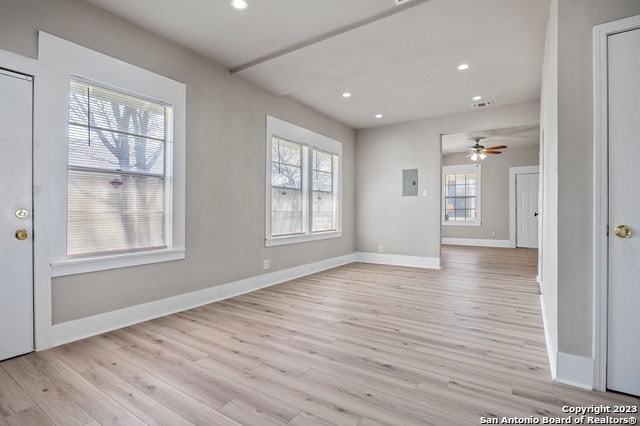 empty room with plenty of natural light, ceiling fan, and light hardwood / wood-style flooring