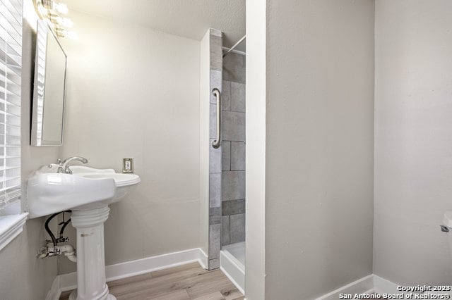 bathroom with hardwood / wood-style flooring and tiled shower