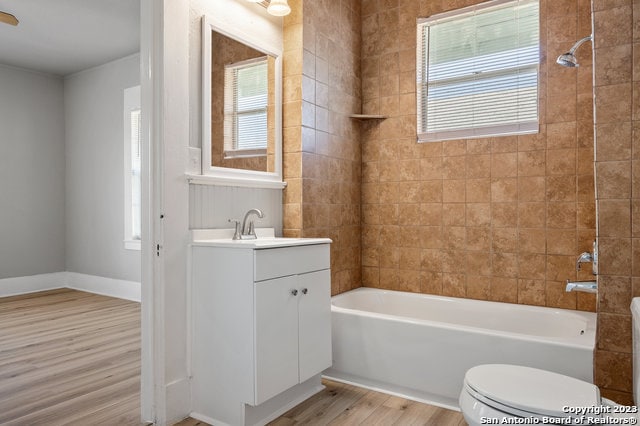 full bathroom featuring hardwood / wood-style floors, plenty of natural light, tiled shower / bath combo, and vanity