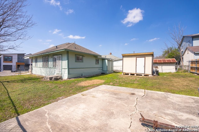 rear view of property featuring an outdoor structure, a yard, and a patio area