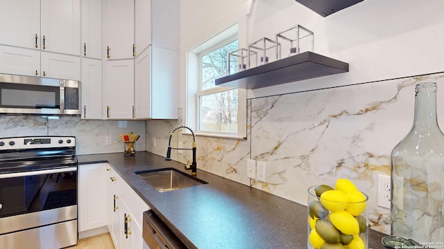 kitchen with white cabinets, backsplash, appliances with stainless steel finishes, and sink