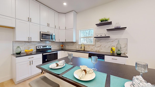 kitchen with white cabinetry, backsplash, appliances with stainless steel finishes, sink, and light wood-type flooring