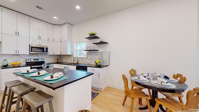 kitchen featuring backsplash, stainless steel appliances, light hardwood / wood-style flooring, and sink