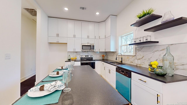 kitchen with white cabinets, tasteful backsplash, sink, and stainless steel appliances