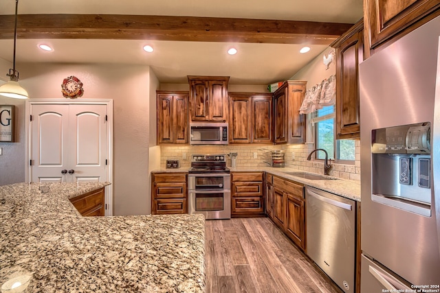 kitchen featuring decorative light fixtures, beamed ceiling, light hardwood / wood-style floors, sink, and stainless steel appliances