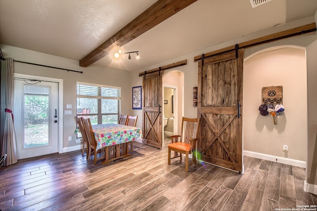 dining area with a barn door, beam ceiling, and dark hardwood / wood-style floors