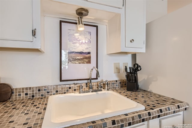 kitchen featuring white cabinets, tasteful backsplash, sink, and pendant lighting