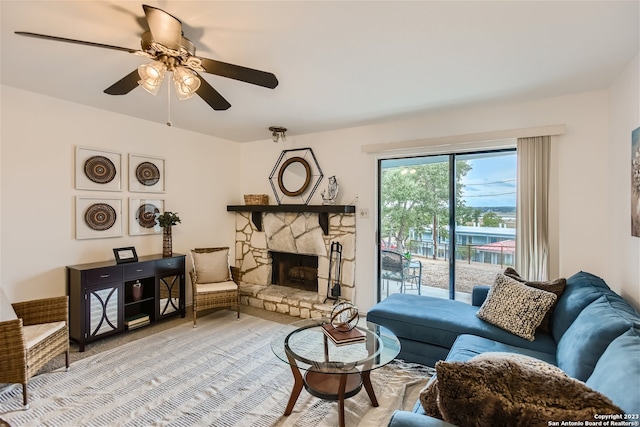 living room with a stone fireplace and ceiling fan