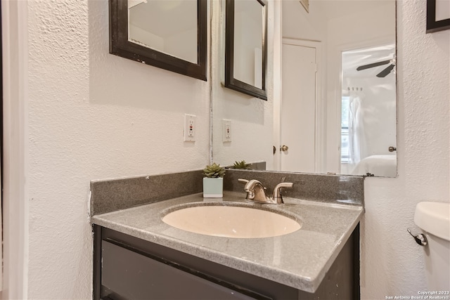 bathroom with toilet, vanity, and ceiling fan