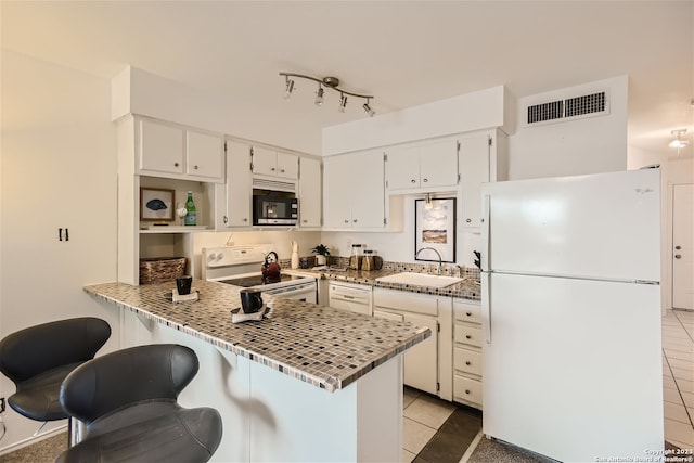 kitchen with light tile flooring, sink, white appliances, and white cabinets