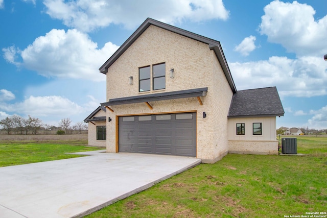 view of front of home featuring a front yard, central AC unit, and a garage