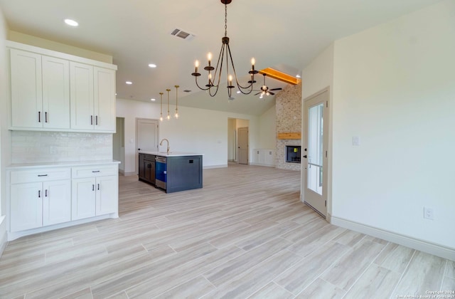 kitchen with hanging light fixtures, white cabinetry, a fireplace, an inviting chandelier, and blue cabinets