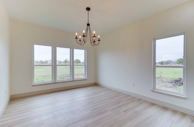 spare room featuring a notable chandelier and light hardwood / wood-style flooring