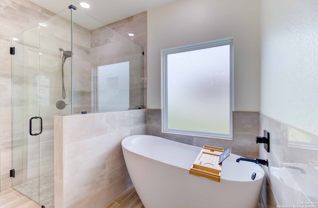 bathroom featuring tile walls, independent shower and bath, and a healthy amount of sunlight