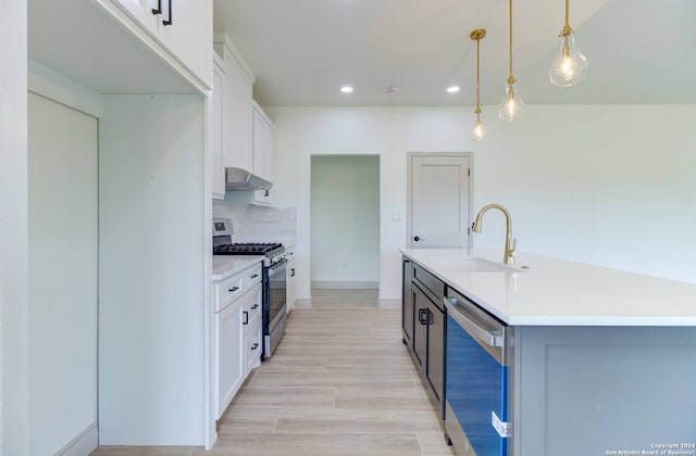 kitchen featuring a kitchen island with sink, stainless steel appliances, decorative light fixtures, and white cabinetry