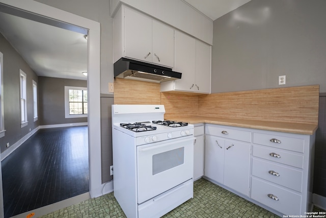 kitchen featuring white cabinets, dark tile floors, and white gas range