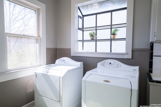 laundry room with tile walls, separate washer and dryer, and a healthy amount of sunlight