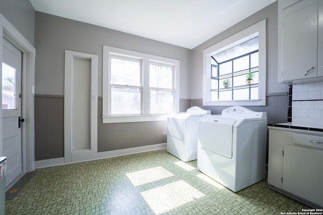 clothes washing area with cabinets, independent washer and dryer, light tile floors, and a wealth of natural light