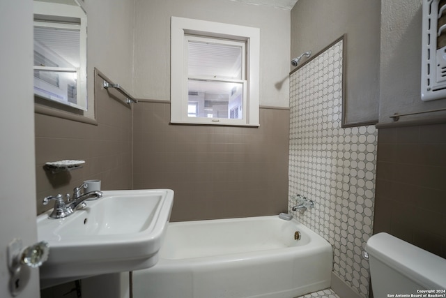 full bathroom featuring tiled shower / bath combo, toilet, and sink