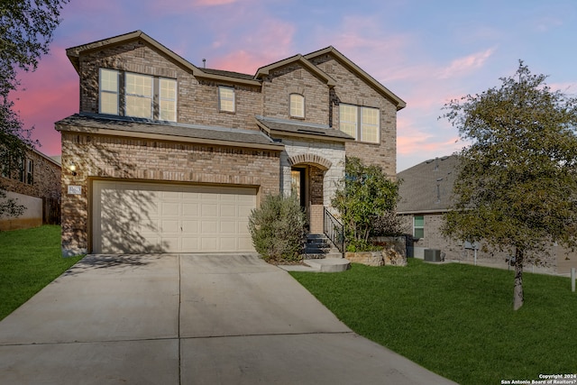 view of front facade with a garage, central AC unit, and a lawn