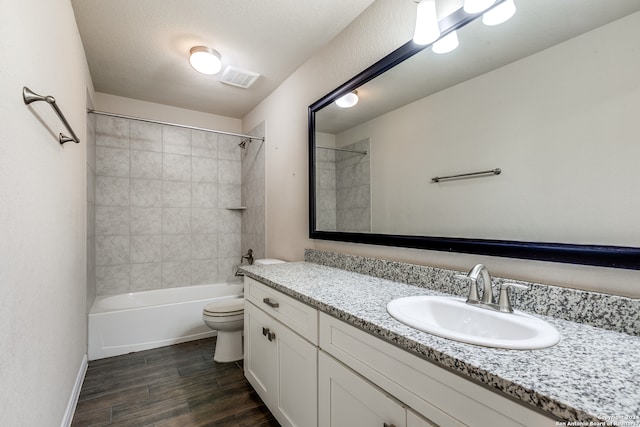 full bath with toilet, wood finished floors, vanity, visible vents, and washtub / shower combination