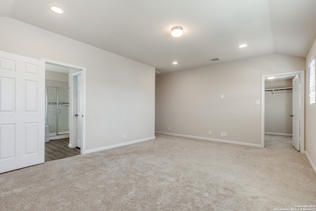 unfurnished bedroom with lofted ceiling, recessed lighting, visible vents, carpet, and a walk in closet