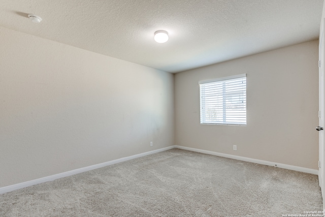 carpeted spare room featuring baseboards and a textured ceiling