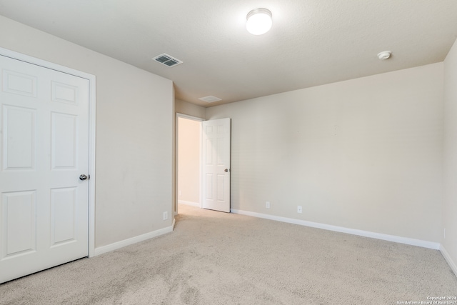 unfurnished bedroom featuring carpet floors, visible vents, a textured ceiling, and baseboards