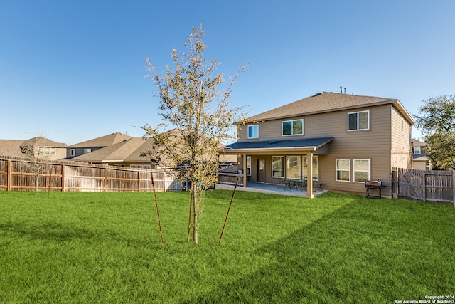 back of house featuring a lawn, a patio area, and a fenced backyard