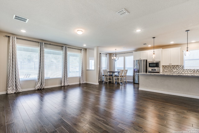 unfurnished living room featuring dark wood-style flooring, visible vents, and a textured ceiling